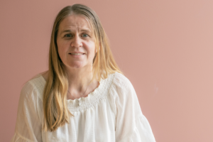 Solbjørg stående foran en beige vegg. Foto