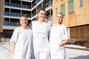 3 sykepleierstudenter poserer foran ett sykehjem. Foto: Sykehjemsetaten, Oslo kommune.