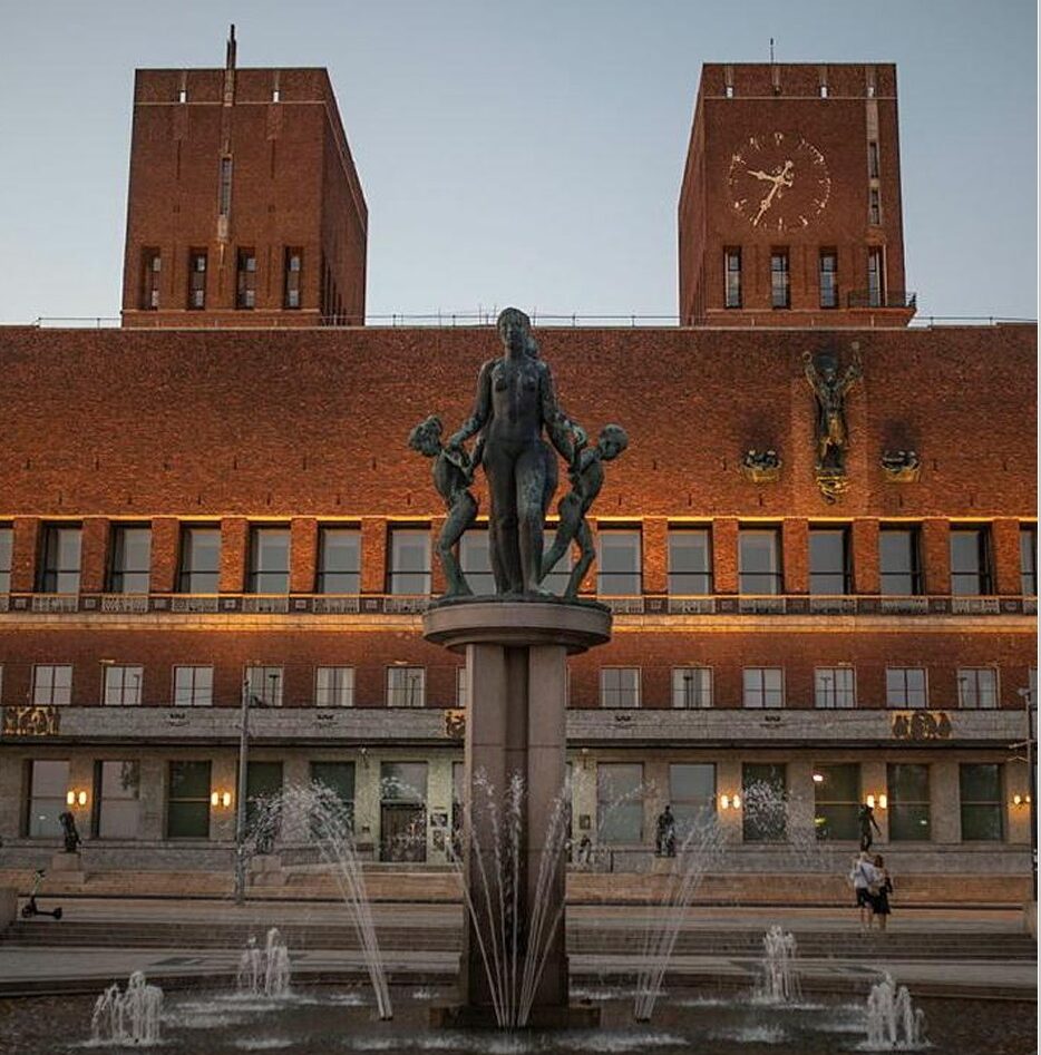 Fasaden til Oslo Rådhus, med statue stående foran. Fotografi