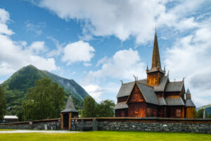 Stavkirke med fjell i bakgrunnen. Foto