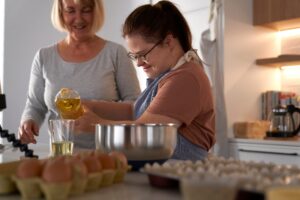 Ung kvinne med downs syndrom som baker, med bistand fra annen kvinne.