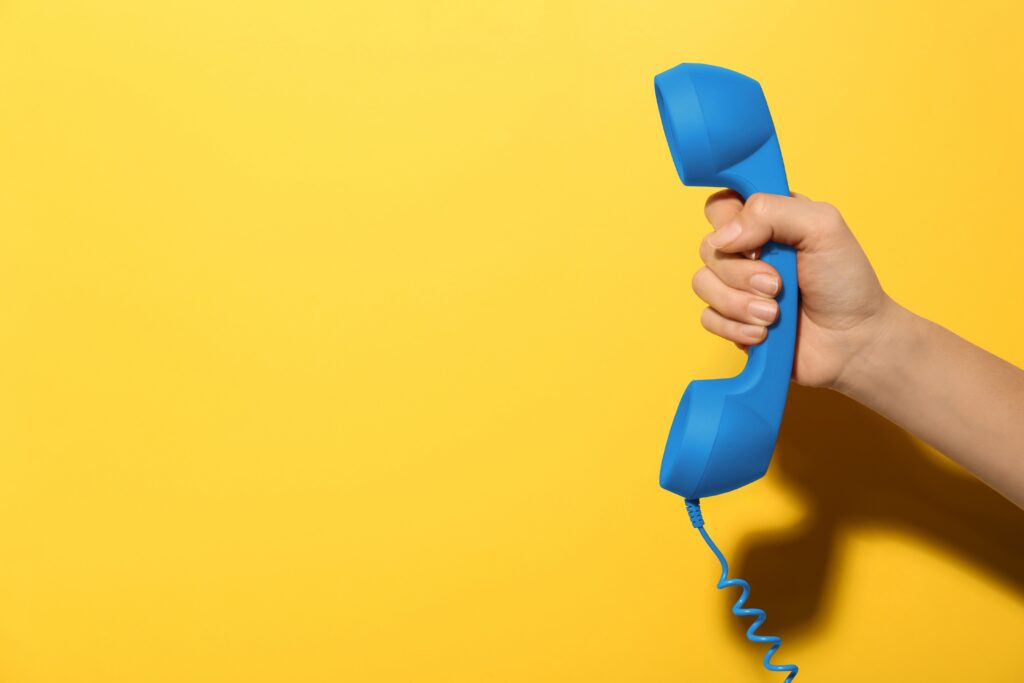 En hånd holder et blått telefonrør. Foto