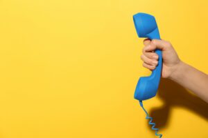 En hånd holder et blått telefonrør. Foto