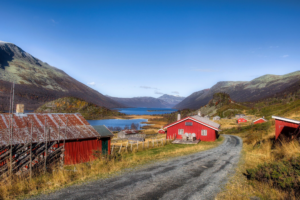 Eldre seterbygninger ved vakker innsjø på fjellet.