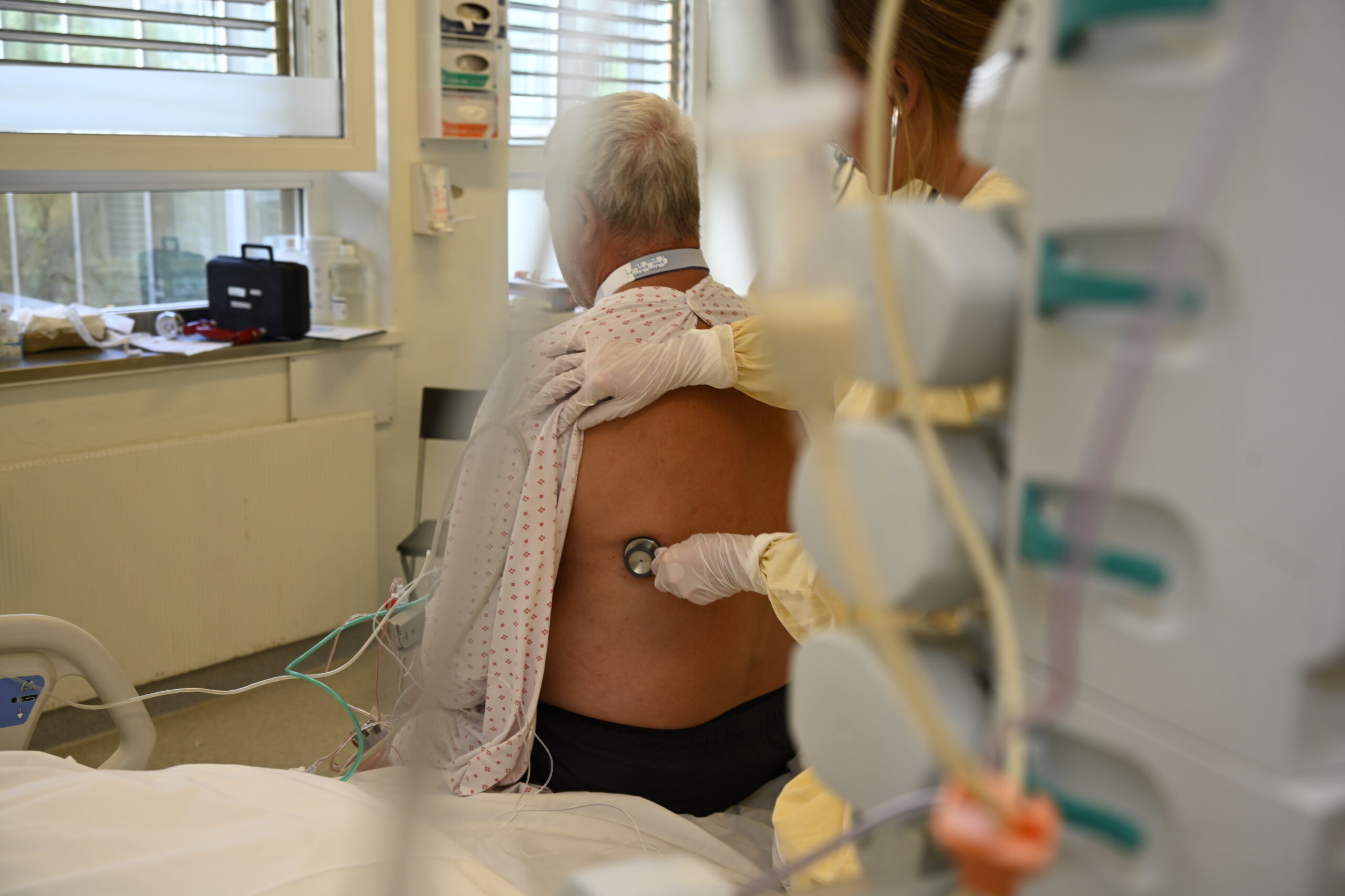 Helsepersonell undersøker ryggen til pasient, simuleringssituasjon i pasientrom, foto