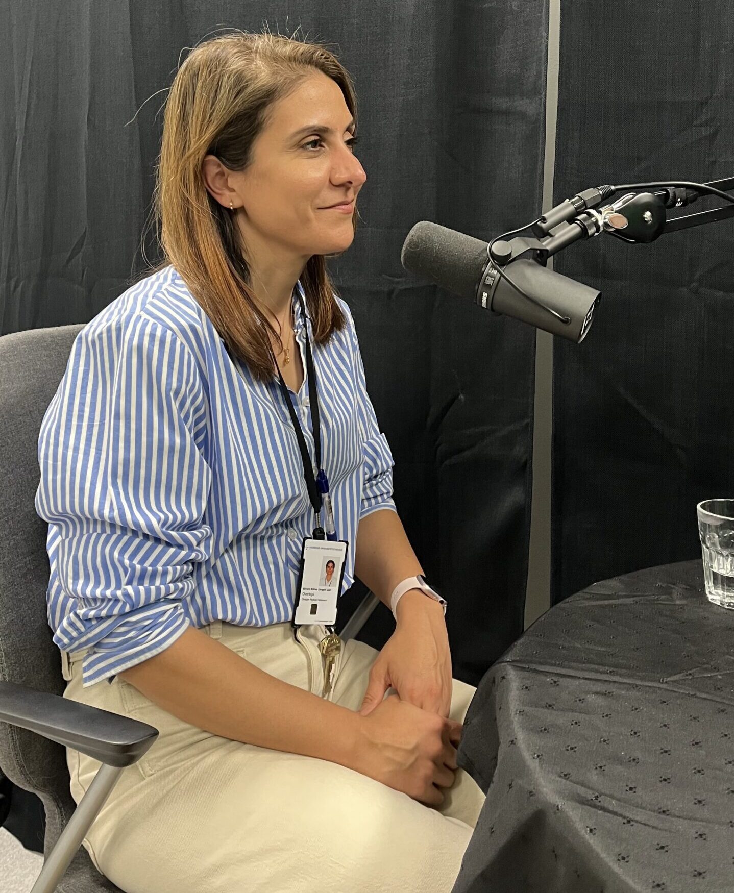 podkast-gjest Miriam Sengani-Jar under innspilling, sittende foran en mikrofon. Sort bakgrunn