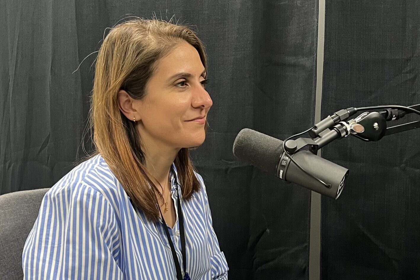 podkast-gjest Miriam Sengani-Jar under innspilling, sittende foran en mikrofon. Sort bakgrunn